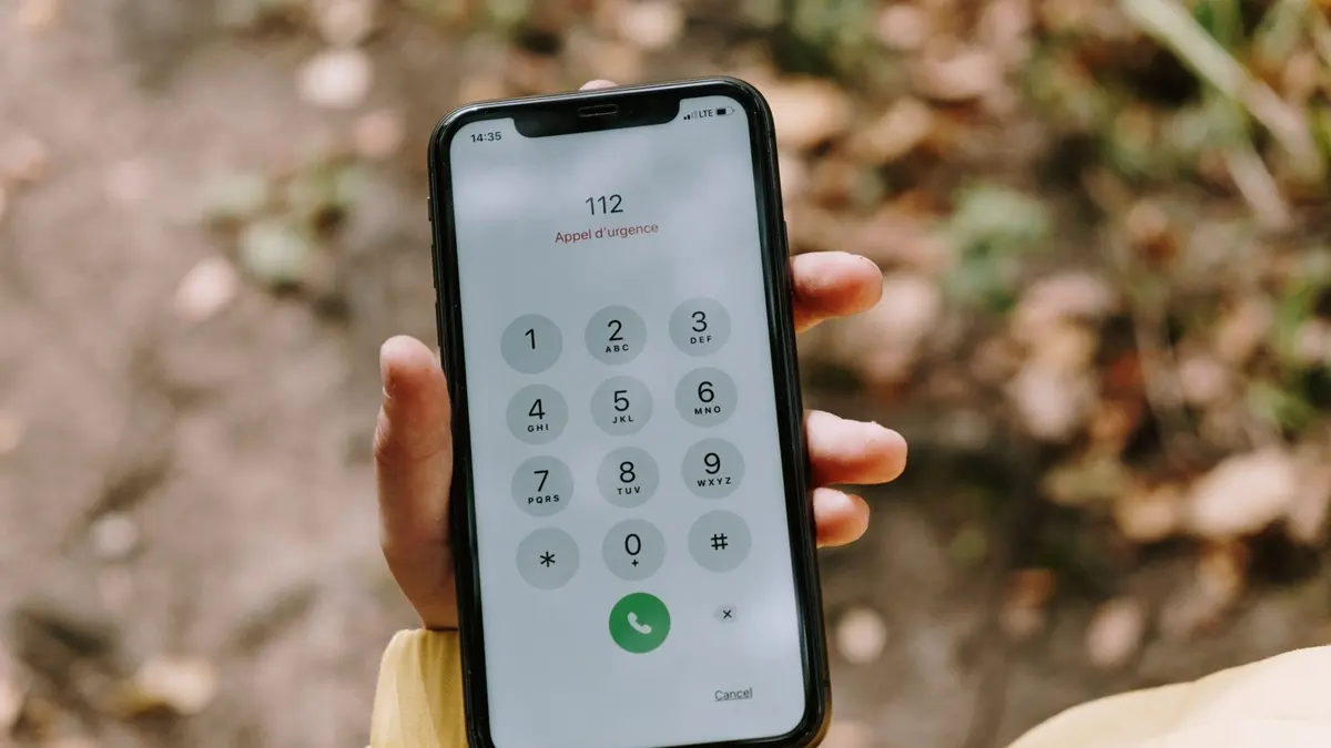 Smartphone affichant un appel entrant inconnu sur un bureau, carnet de notes et café à côté